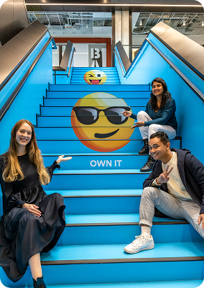 Photo of 2degrees staff members sitting on the stairs with an emoji showing our Own It value