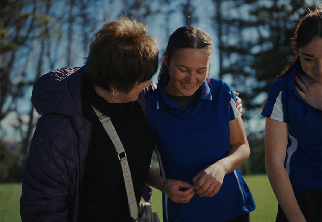 Photo of a player coming off the field with a supporter giving her a hug and making her smile