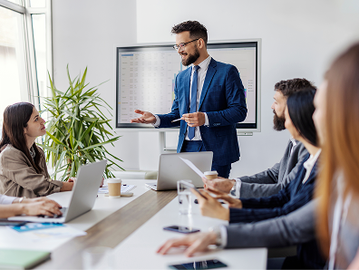 Young leader standing at meeting room with his team around conference table of experts