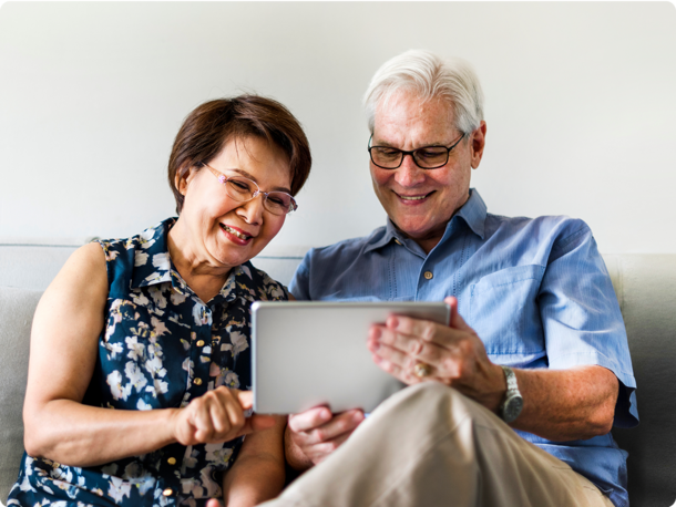 Elderly couple sitting on a couch looking at a tablet together