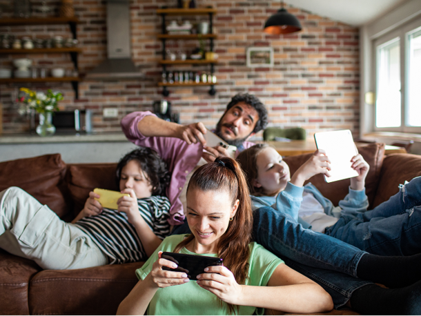 Family sitting on a couch and playing on mobile phones and tablets