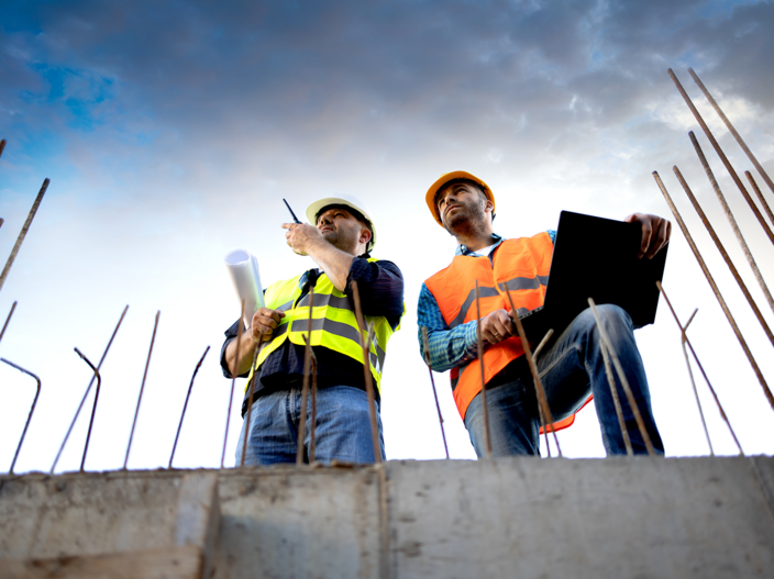 Two men standing at a worksite in high visibility vest